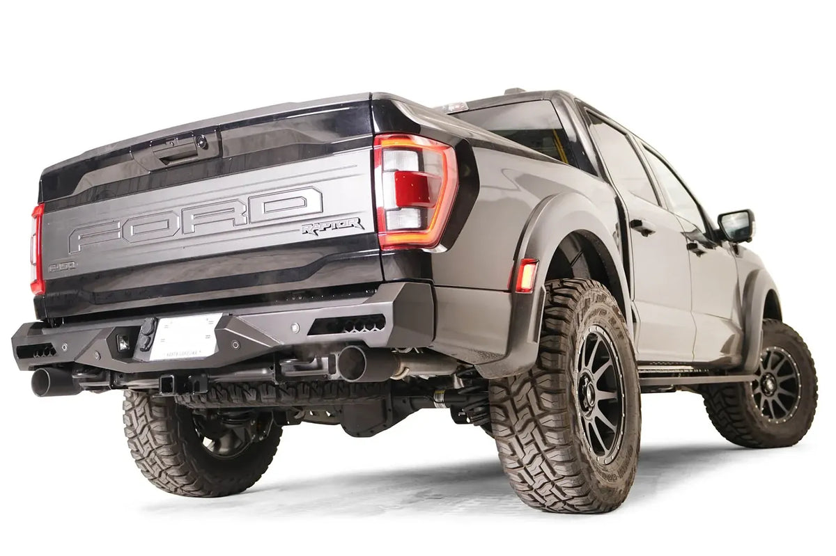Fab Fours Vengeance rear bumper on a dark gray Ford F-150 Raptor, rear passenger-side three-quarter view, showing the bumper end cap, corner light and hitch receiver area