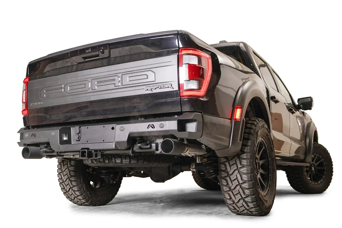 Fab Fours Premium rear bumper on a dark gray Ford F-150 Raptor, rear passenger-side three-quarter view, showing the bumper end cap, integrated lights and hitch receiver area
