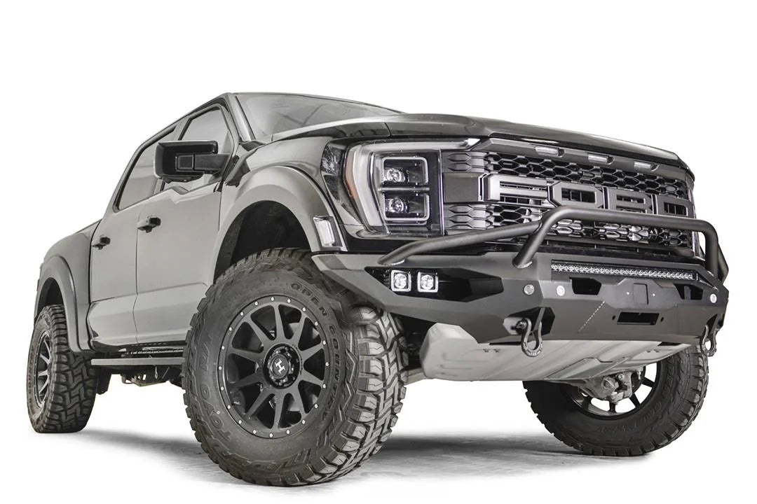 Fab Fours Matrix front winch bumper with pre-runner guard on a gray Ford F-150 Raptor, front passenger-side three-quarter view, showing the tubular pre-runner hoop, center light bar and pod lights