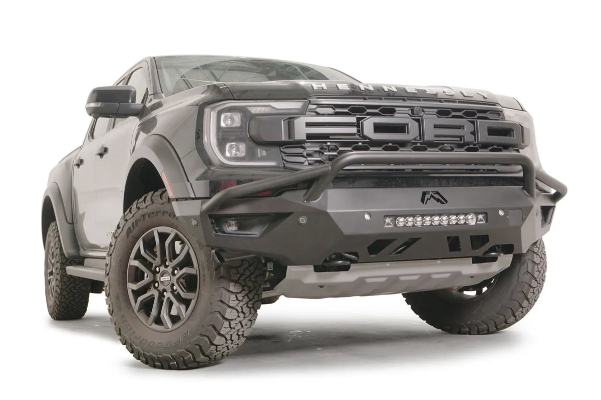 Fab Fours Vengeance front bumper with pre-runner guard on a gray Ford Ranger Raptor, front driver-side three-quarter view, showing the pre-runner hoop, light bar and angular bumper wing