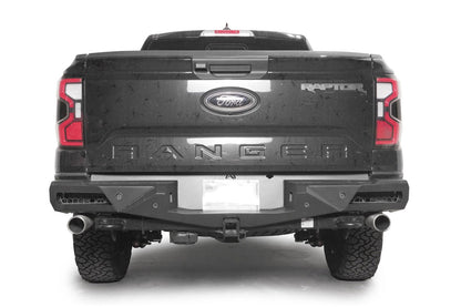 Fab Fours Vengeance rear bumper on a dark gray Ford Ranger Raptor, straight rear view, with honeycomb mesh light openings, parking sensors, center license plate area, and hitch receiver