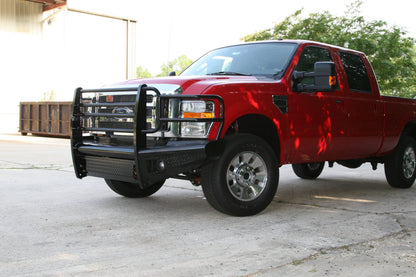 Fab Fours Black Steel front ranch bumper with full guard on a red Ford Super Duty outdoors, front driver-side three-quarter view, showing the full grille guard, headlight hoops and diamond-plate face