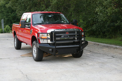 Fab Fours Black Steel front ranch bumper with full guard on a red Ford Super Duty outdoors, front passenger-side three-quarter view, showing the full tubular grille guard, diamond-plate face and bumper wing