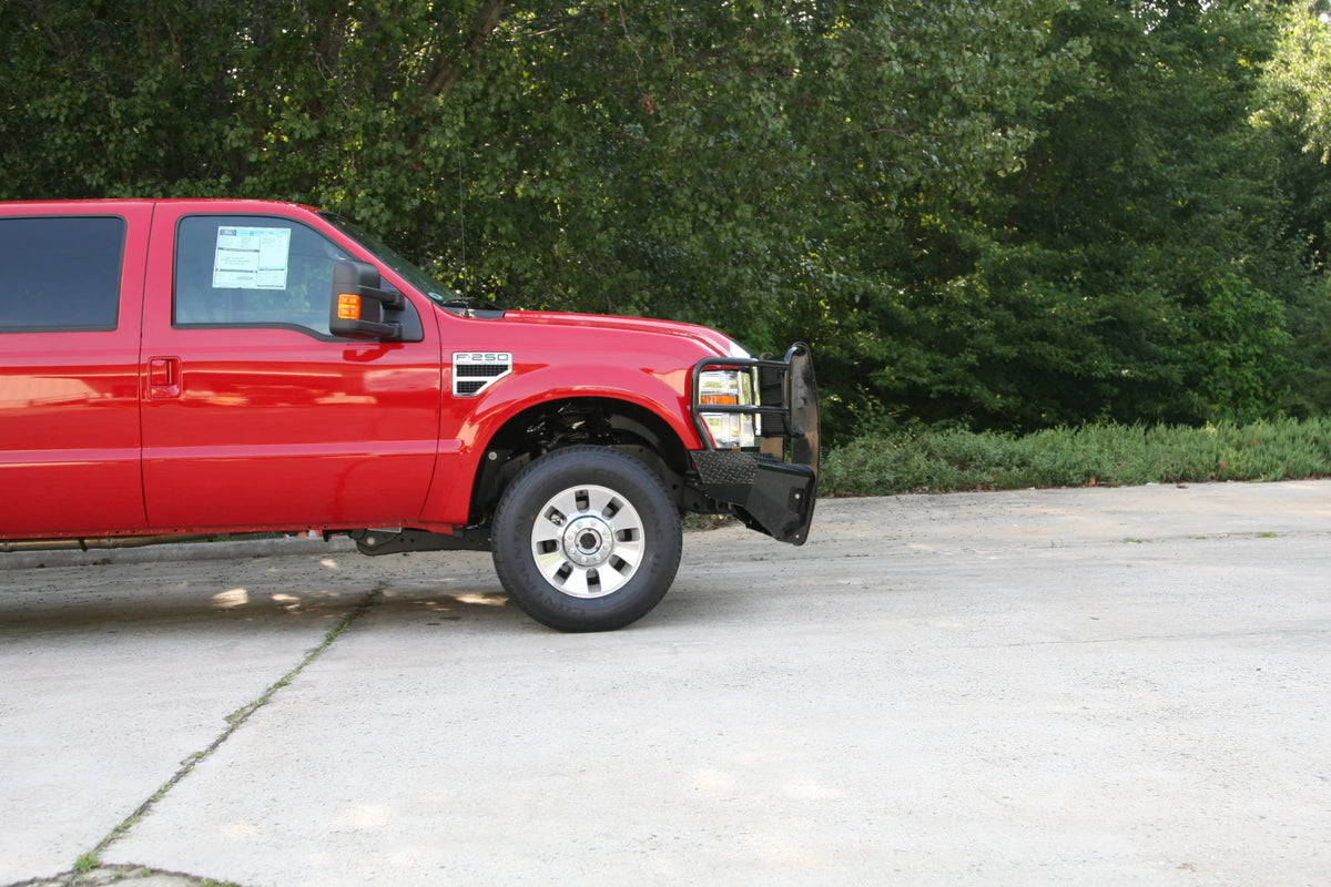 Fab Fours Black Steel front ranch bumper with full guard on a red Ford Super Duty outdoors, passenger-side profile view, showing the grille guard depth and bumper wing clearance