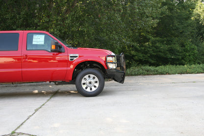 Fab Fours Black Steel front ranch bumper with full guard on a red Ford Super Duty outdoors, passenger-side profile view, showing the grille guard depth and bumper wing clearance