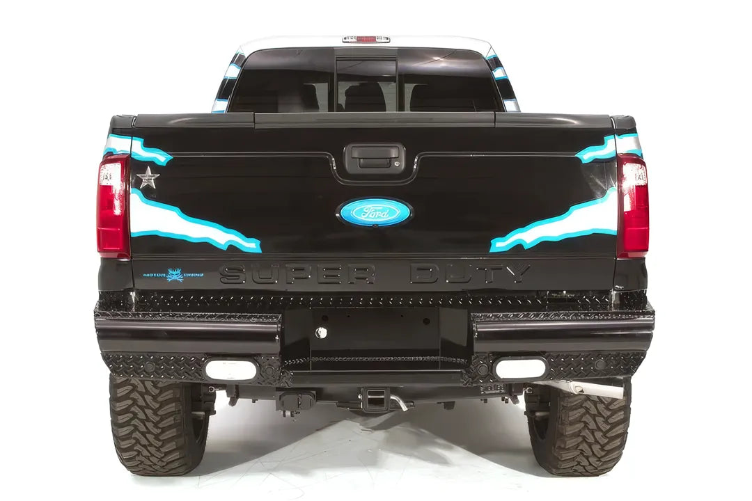 Fab Fours Black Steel ranch rear bumper on a black Ford Super Duty, straight-on rear view, showing the diamond-plate top step, integrated lights and center hitch opening