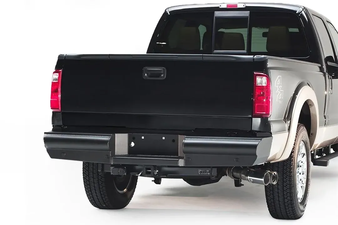 Fab Fours Black Steel Elite rear bumper on a black Ford Super Duty, rear passenger-side three-quarter view, showing the smooth bumper face, end cap and license plate recess