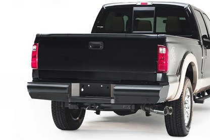 Fab Fours Black Steel Elite rear bumper on a black Ford Super Duty, rear passenger-side three-quarter view, showing the smooth bumper face, end cap and license plate recess