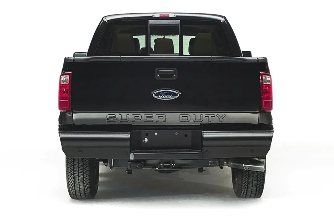 Fab Fours Black Steel Elite rear bumper on a black Ford Super Duty, straight-on rear view, showing the smooth full-width bumper, license plate recess and hitch receiver opening