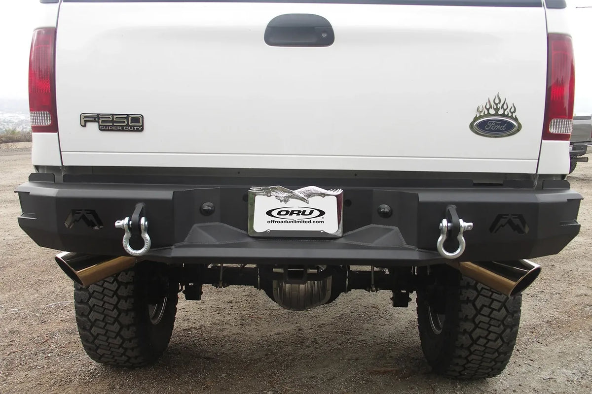 Fab Fours Premium rear bumper on a white Ford F-250 Super Duty outdoors, straight-on rear view, showing the full-width bumper, D-ring shackles and Fab Fours logo cutouts