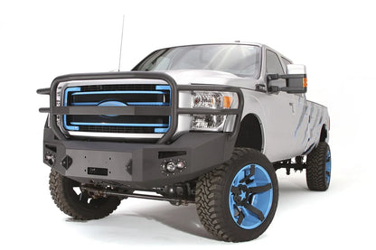 Fab Fours Premium Heavy Duty winch front bumper with full guard on a silver Ford Super Duty, front driver-side three-quarter view, showing the full tubular grille guard, winch opening and integrated lights