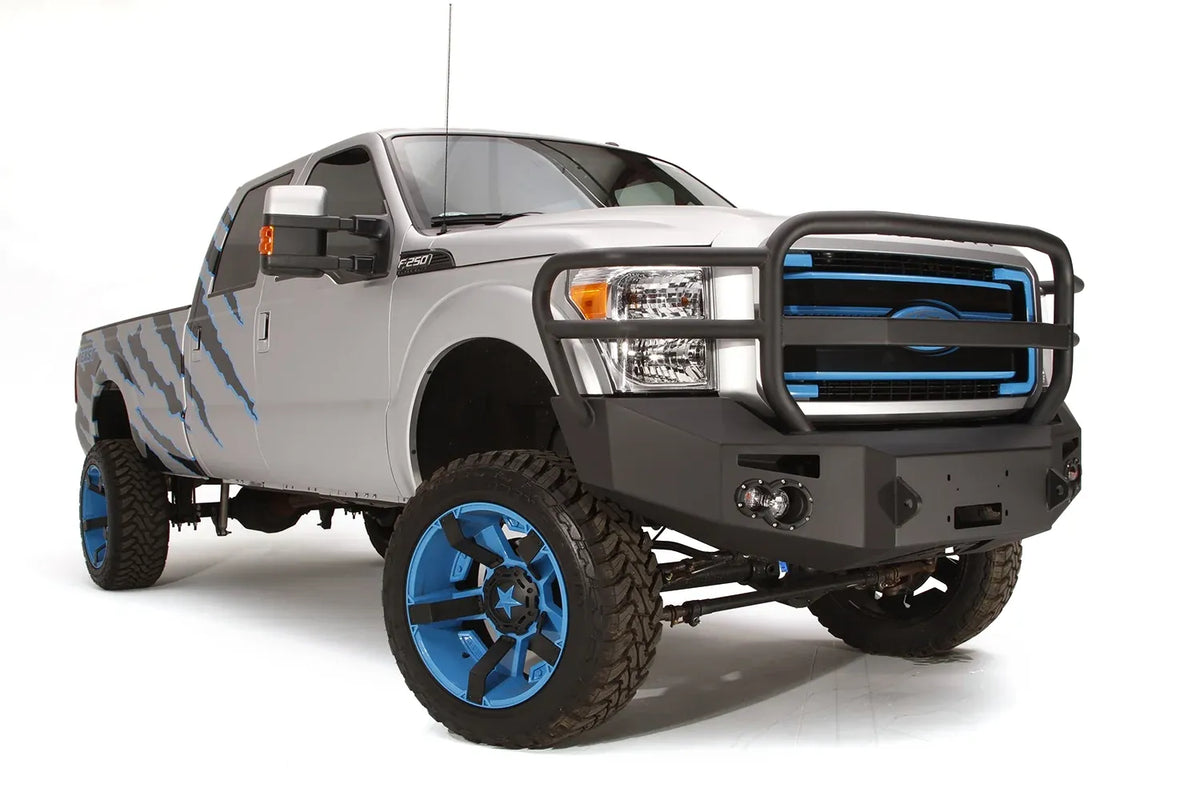 Fab Fours Premium Heavy Duty winch front bumper with full guard on a silver Ford Super Duty, front passenger-side three-quarter view, showing the full grille guard, headlight hoops and integrated lights