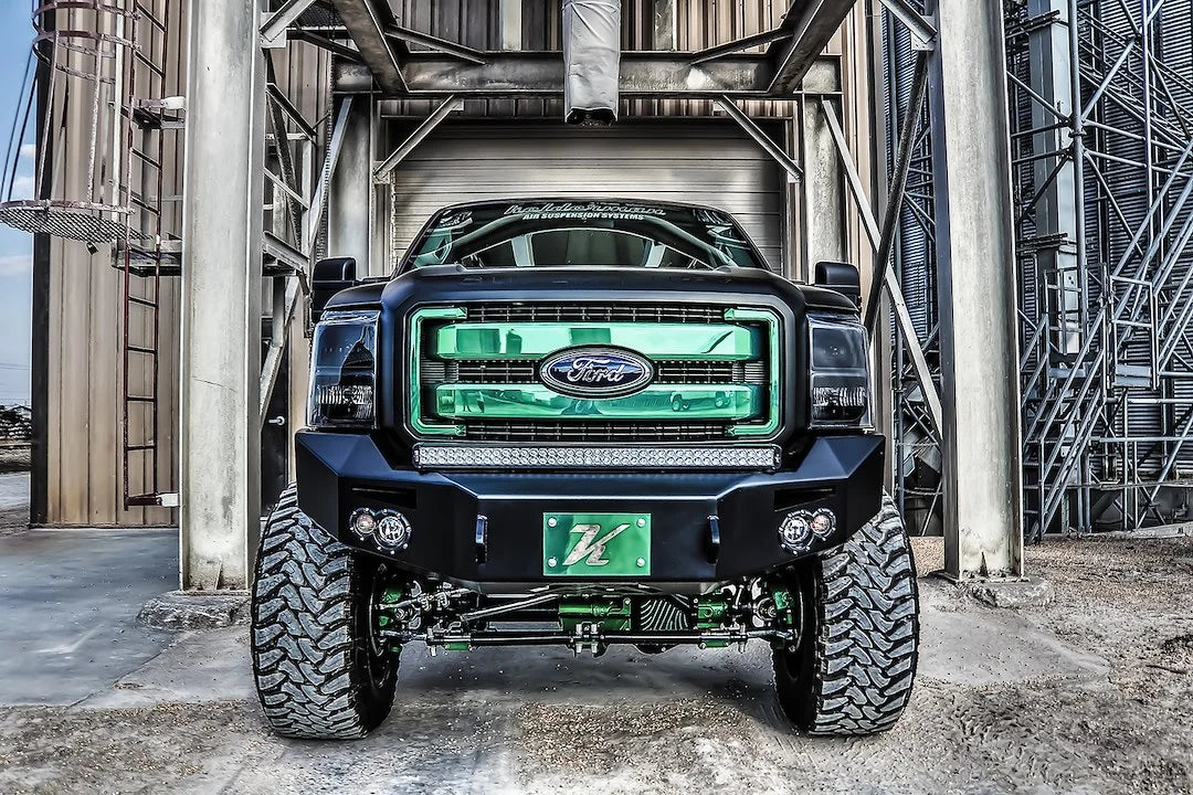 Fab Fours Premium Heavy Duty winch front bumper on a black Ford Super Duty outdoors, straight-on front view, showing the bumper face, integrated lights and center light bar above