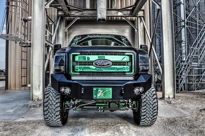 Fab Fours Premium Heavy Duty winch front bumper on a black Ford Super Duty outdoors, straight-on front view, showing the bumper face, integrated lights and center light bar above