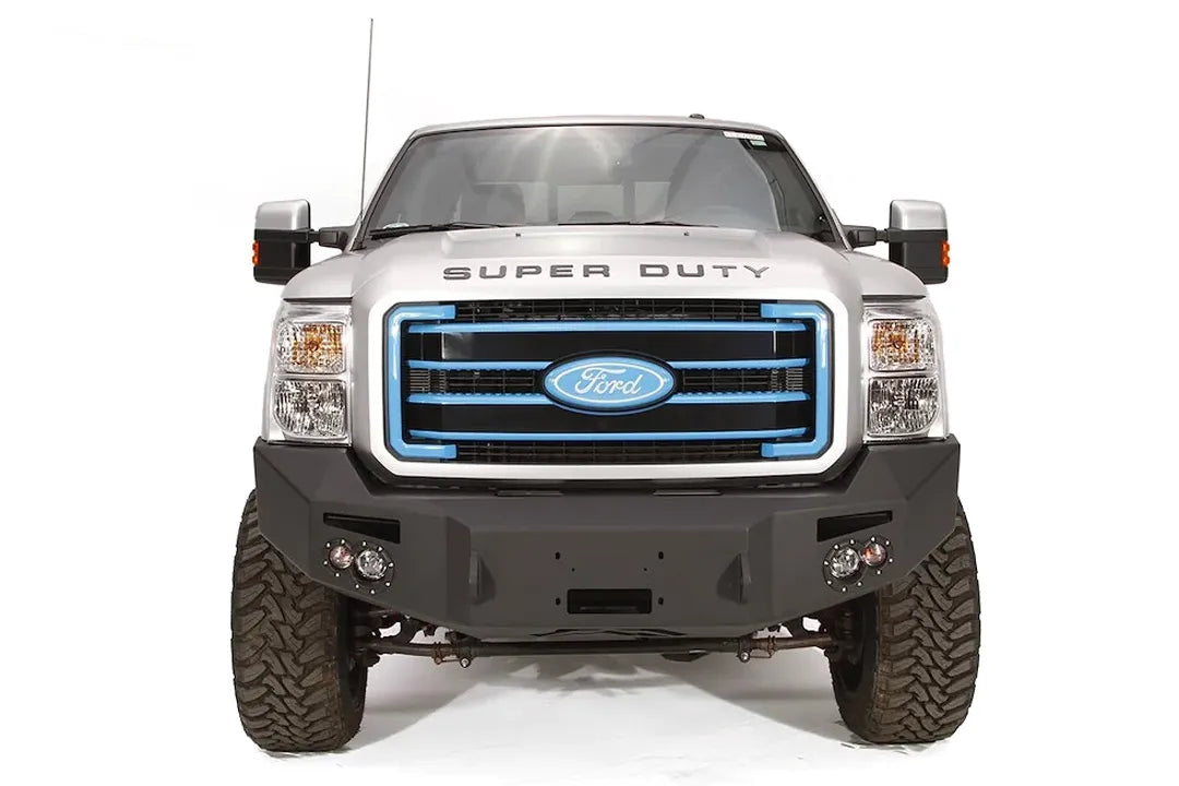 Fab Fours Premium Heavy Duty winch front bumper on a silver Ford Super Duty, straight-on front view, showing the winch opening, integrated lights and wraparound wings