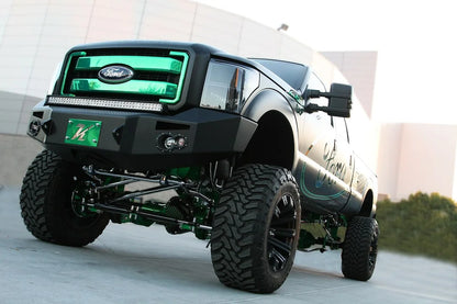 Fab Fours Premium Heavy Duty winch front bumper on a black Ford Super Duty outdoors, front driver-side three-quarter view, showing the bumper face, integrated lights and bumper wing