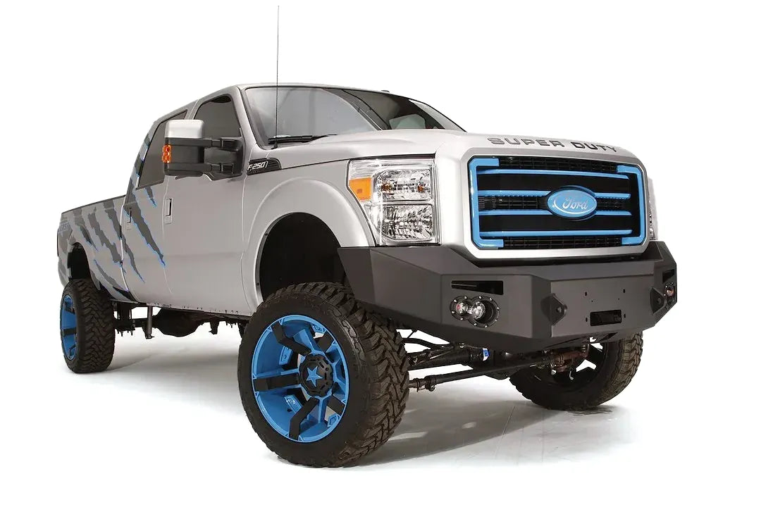 Fab Fours Premium Heavy Duty winch front bumper on a silver Ford Super Duty, front passenger-side three-quarter view, showing the winch opening, integrated lights and bumper wing