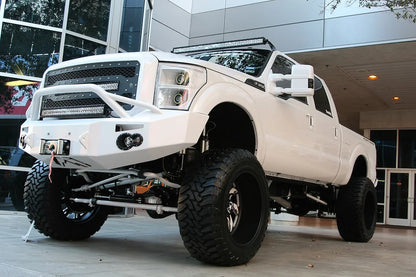 Fab Fours Premium Heavy Duty winch front bumper with pre-runner guard in white on a white Ford Super Duty outdoors, front driver-side three-quarter view, showing the pre-runner hoop, winch and integrated lights