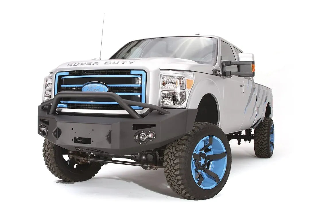 Fab Fours Premium Heavy Duty winch front bumper with pre-runner guard on a silver Ford Super Duty, front driver-side three-quarter view, showing the pre-runner hoop, winch opening and bumper end cap