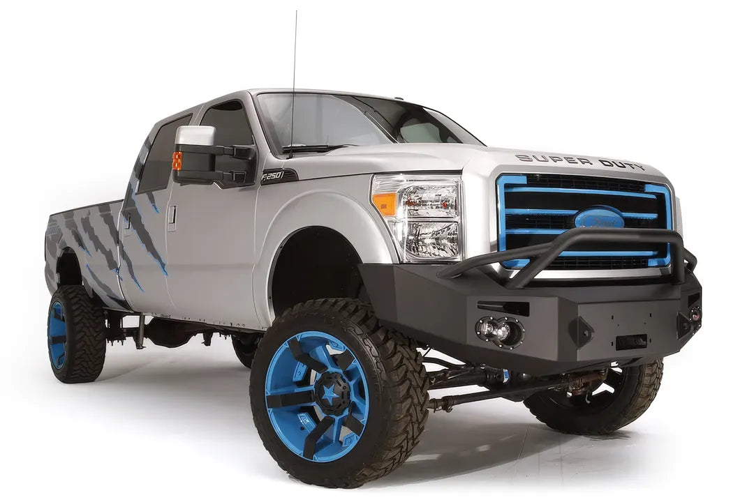 Fab Fours Premium Heavy Duty winch front bumper with pre-runner guard on a silver Ford Super Duty, front passenger-side three-quarter view, showing the pre-runner hoop, integrated lights and bumper wing