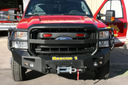 Fab Fours Premium Heavy Duty winch front bumper with full guard on a red Ford Super Duty outdoors, straight-on front view, showing the full grille guard, winch with hook and integrated lights