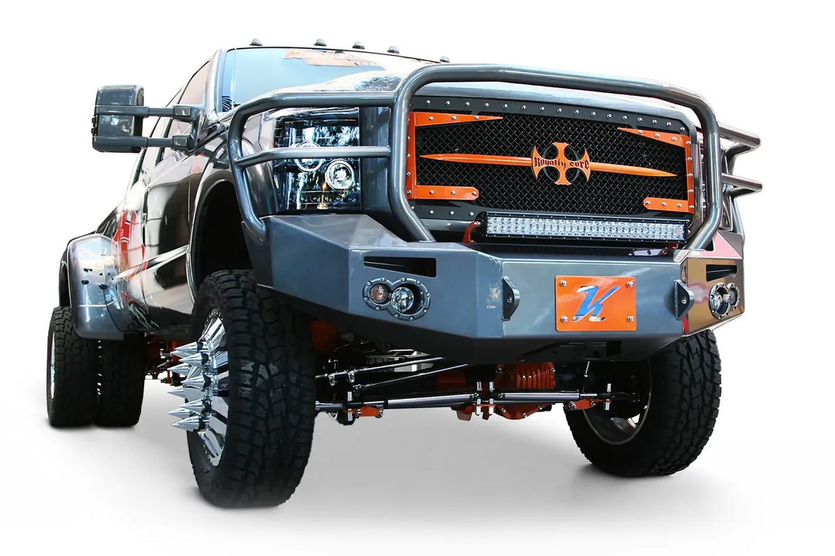 Fab Fours Premium Heavy Duty winch front bumper with full guard on a wrapped white Ford Super Duty dually outdoors, front passenger-side three-quarter view, showing the full grille guard, integrated lights and bumper wing