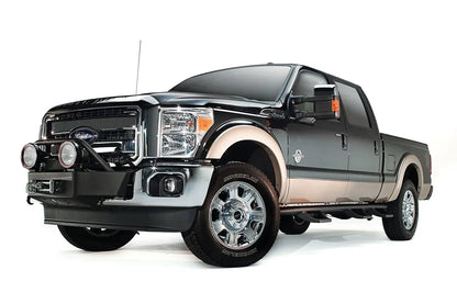 Fab Fours large frame winch mount on a black and tan Ford Super Duty, front driver-side three-quarter view, showing the winch cradle, light hoop and round off-road lights
