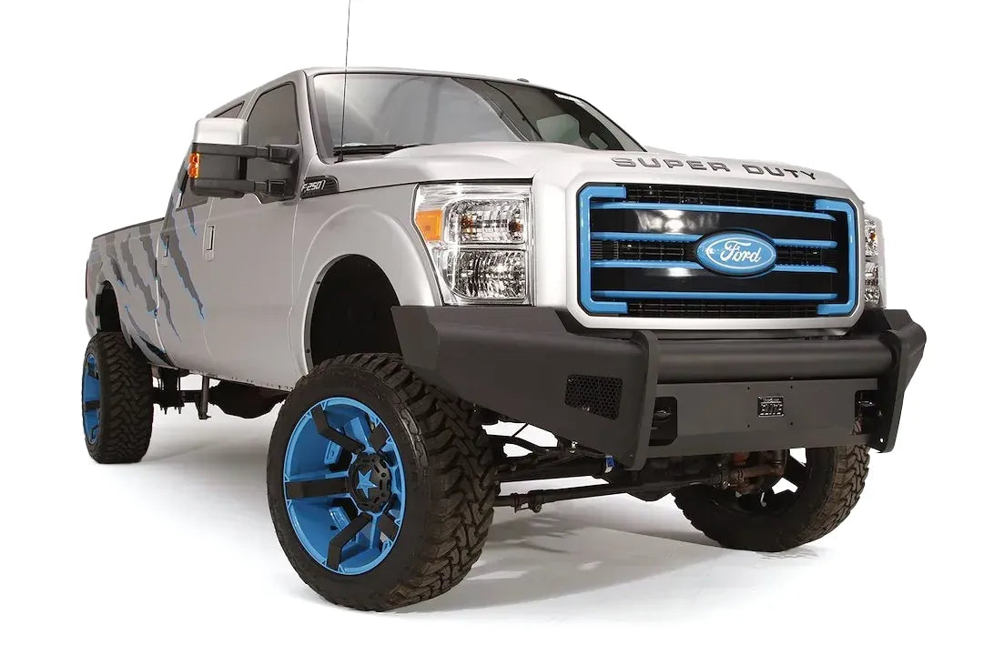 Fab Fours Black Steel Elite front bumper on a silver Ford Super Duty, front passenger-side three-quarter view, showing the smooth plate face, mesh wing inserts and Elite badge