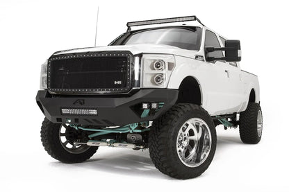 Fab Fours Vengeance front bumper on a white Ford Super Duty, front driver-side three-quarter view, showing the center light bar, Fab Fours logo cutout and pod light pockets