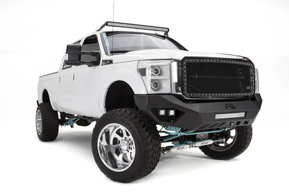 Fab Fours Vengeance front bumper on a white Ford Super Duty, front passenger-side three-quarter view, showing the center light bar, pod lights and angular bumper wing