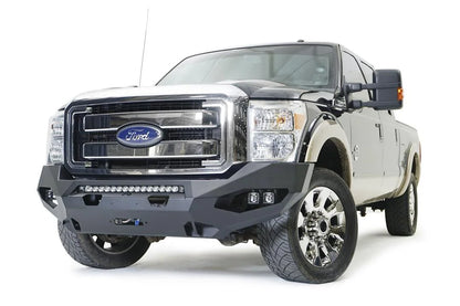 Fab Fours Matrix front winch bumper on a black and tan Ford Super Duty, front driver-side three-quarter view, showing the center light bar, pod lights and winch opening