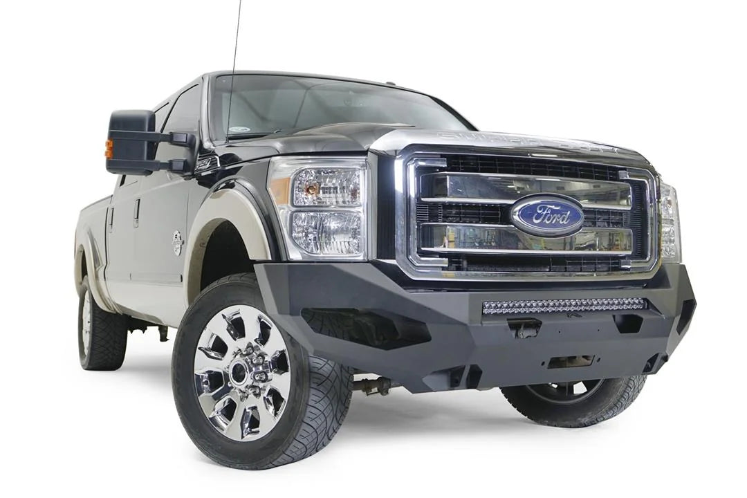 Fab Fours Matrix front winch bumper on a black and tan Ford Super Duty, front passenger-side three-quarter view, showing the center light bar, angular wing cutouts and winch opening