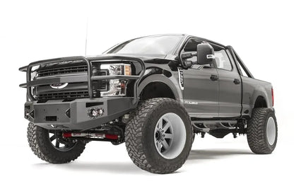 Fab Fours Premium winch front bumper with full guard on a black Ford Super Duty, front driver-side three-quarter view, showing the full tubular grille guard, winch opening and integrated lights