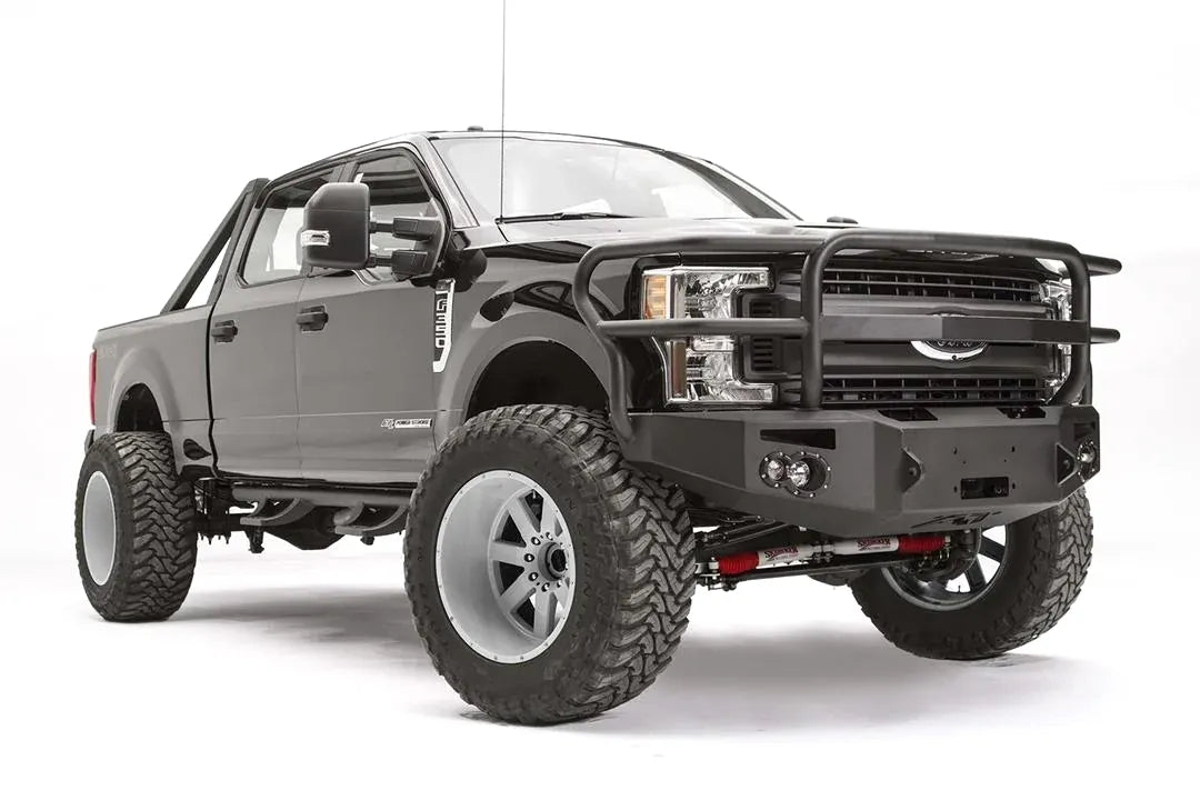 Fab Fours Premium winch front bumper with full guard on a black Ford Super Duty, front passenger-side three-quarter view, showing the full grille guard, headlight hoops and integrated lights