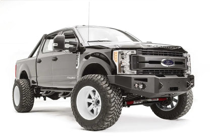Fab Fours Premium winch front bumper on a black Ford Super Duty, front passenger-side three-quarter view, showing the winch opening, integrated lights and bumper wing