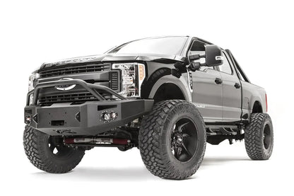 Fab Fours Premium winch front bumper with pre-runner guard on a black Ford Super Duty, front driver-side three-quarter view, showing the tubular pre-runner hoop, winch opening and integrated lights
