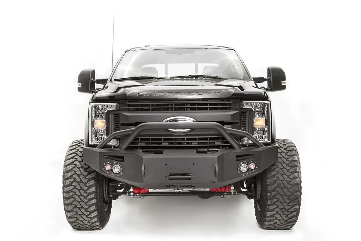 Fab Fours Premium winch front bumper with pre-runner guard on a black Ford Super Duty, straight-on front view, showing the pre-runner hoop, winch opening and pair of integrated lights