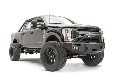 Fab Fours Premium winch front bumper with pre-runner guard on a black Ford Super Duty, front passenger-side three-quarter view, showing the pre-runner hoop, integrated lights and bumper wing