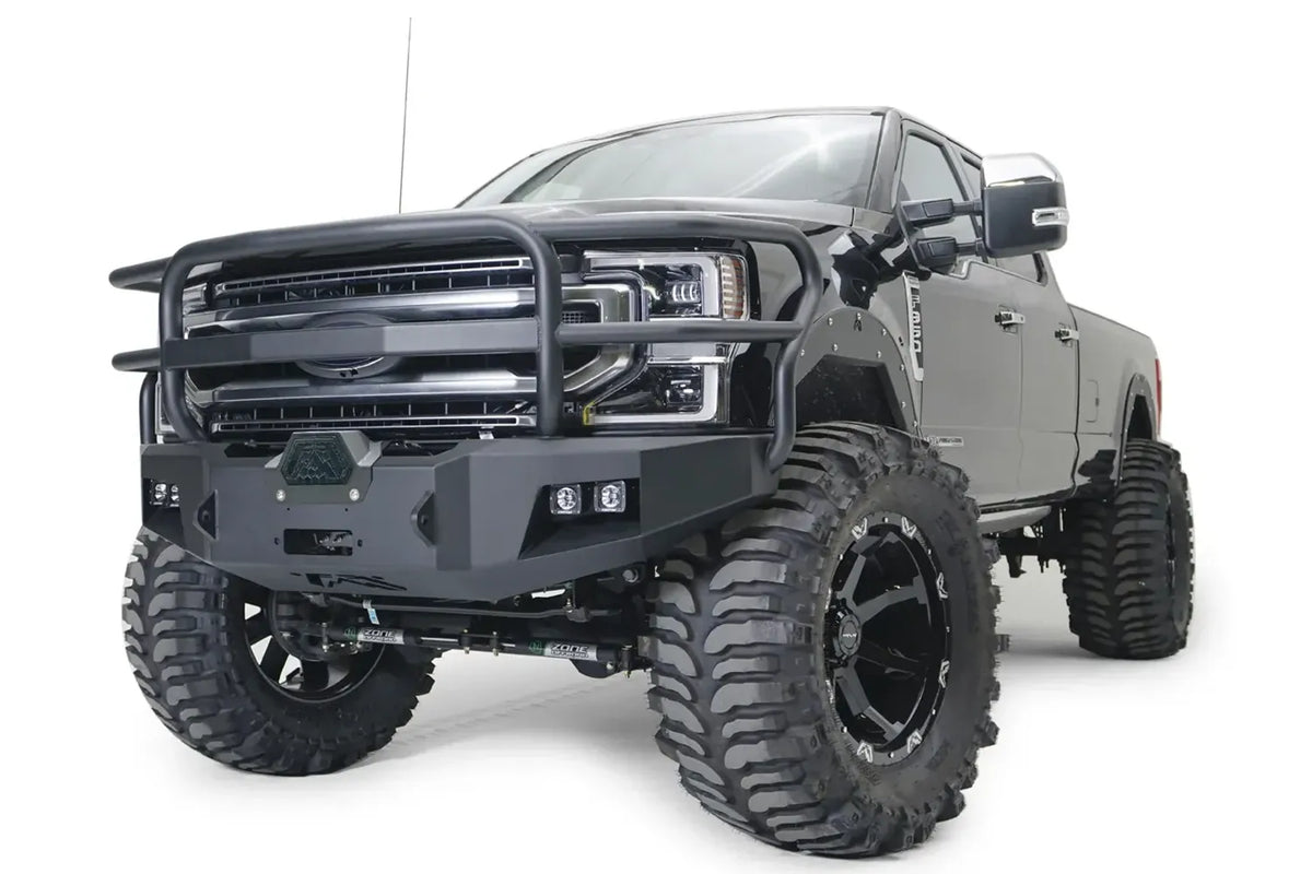 Fab Fours Premium winch front bumper with full guard on a gray Ford Super Duty, front driver-side three-quarter view, showing the full tubular grille guard, winch cover and integrated lights