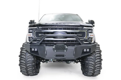 Fab Fours Premium Winch front bumper with pre-runner guard on a black Ford Super Duty, straight-on front view, showing the tubular pre-runner hoop, the center winch opening, flush-mounted LED light pods, and angular steel end caps