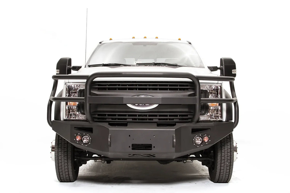 Fab Fours Premium Winch front bumper with full guard on a white Ford Super Duty F-450/F-550, straight-on front view, showing full grille guard hoops, the center winch opening, round light cutouts, and angular steel end caps