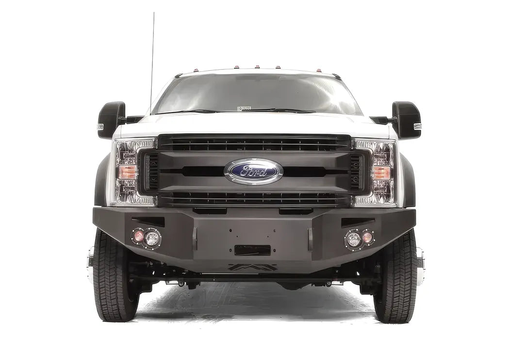 Fab Fours Premium Winch front bumper on a white Ford Super Duty F-450/F-550, straight-on front view, showing the center winch opening, round light cutouts, and angular steel end caps