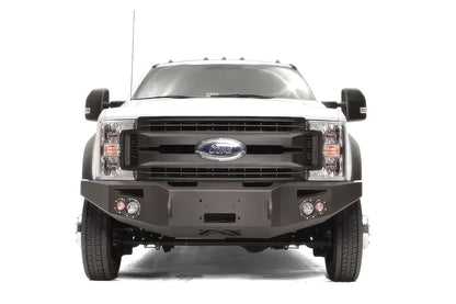 Fab Fours Premium Winch front bumper on a white Ford Super Duty F-450/F-550, straight-on front view, showing the center winch opening, round light cutouts, and angular steel end caps