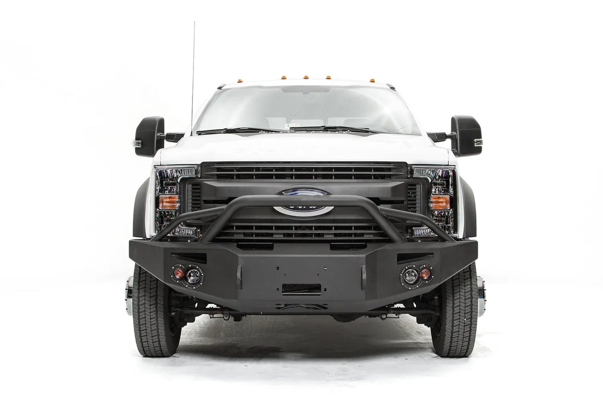 Fab Fours Premium Winch front bumper with pre-runner guard on a white Ford Super Duty F-450/F-550, straight-on front view, showing the tubular pre-runner hoop, the center winch opening, round light cutouts, and angular steel end caps