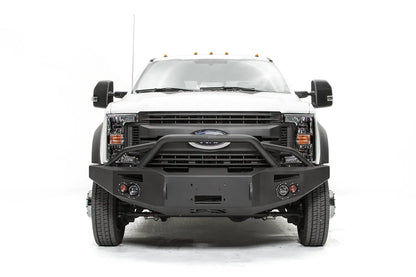 Fab Fours Premium Winch front bumper with pre-runner guard on a white Ford Super Duty F-450/F-550, straight-on front view, showing the tubular pre-runner hoop, the center winch opening, round light cutouts, and angular steel end caps