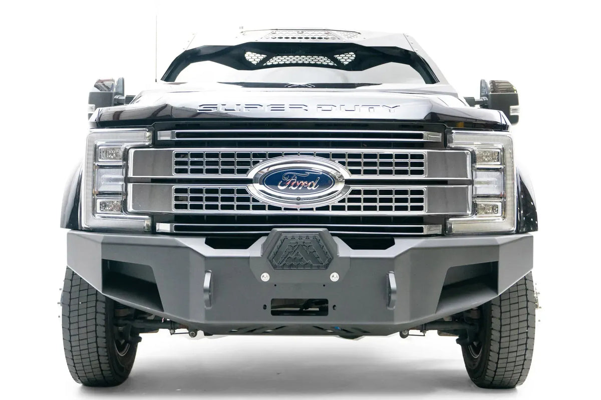 Fab Fours Premium Winch front bumper on a black Ford Super Duty XL F-450/F-550, straight-on front view, showing the center winch opening, angular steel end caps, and integrated tow points