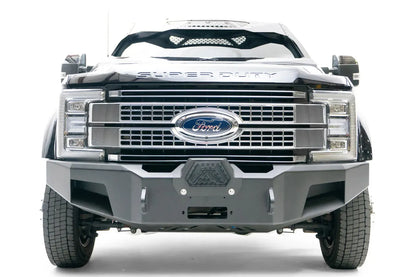 Fab Fours Premium Winch front bumper on a black Ford Super Duty XL F-450/F-550, straight-on front view, showing the center winch opening, angular steel end caps, and integrated tow points