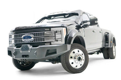 Fab Fours Premium Winch front bumper on a black Ford Super Duty XL F-450/F-550, front driver-side three-quarter view, showing the center winch opening, angular steel end caps, and integrated tow points