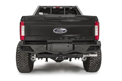 Fab Fours Vengeance rear bumper on a black Ford Super Duty, straight-on rear view, showing honeycomb-pattern side cutouts, the center license plate recess, and angular steel wings