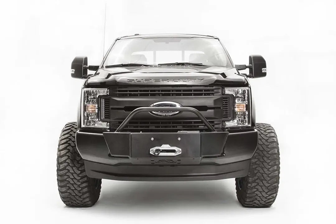 Fab Fours winch mount with pre-runner hoop on a black Ford Super Duty, straight-on front view, showing the winch mount plate with fairlead, the tubular pre-runner hoop, and the factory bumper integration